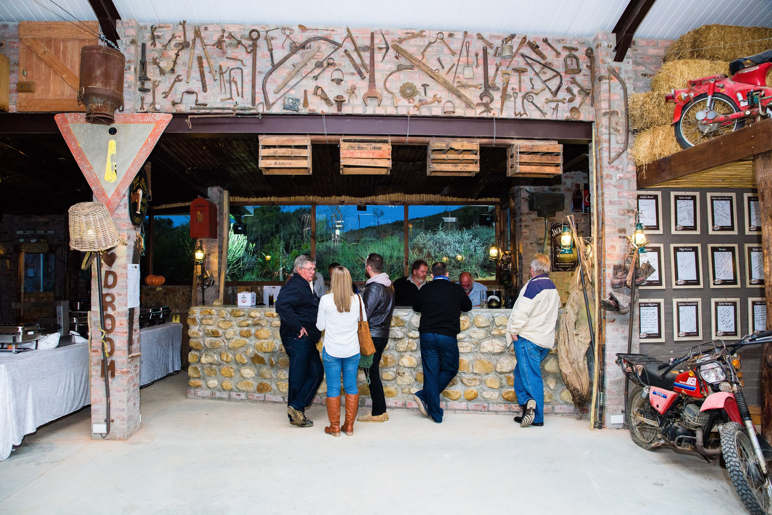 Guests at Kampala’s stone bar beneath a collection of antique tools and objects